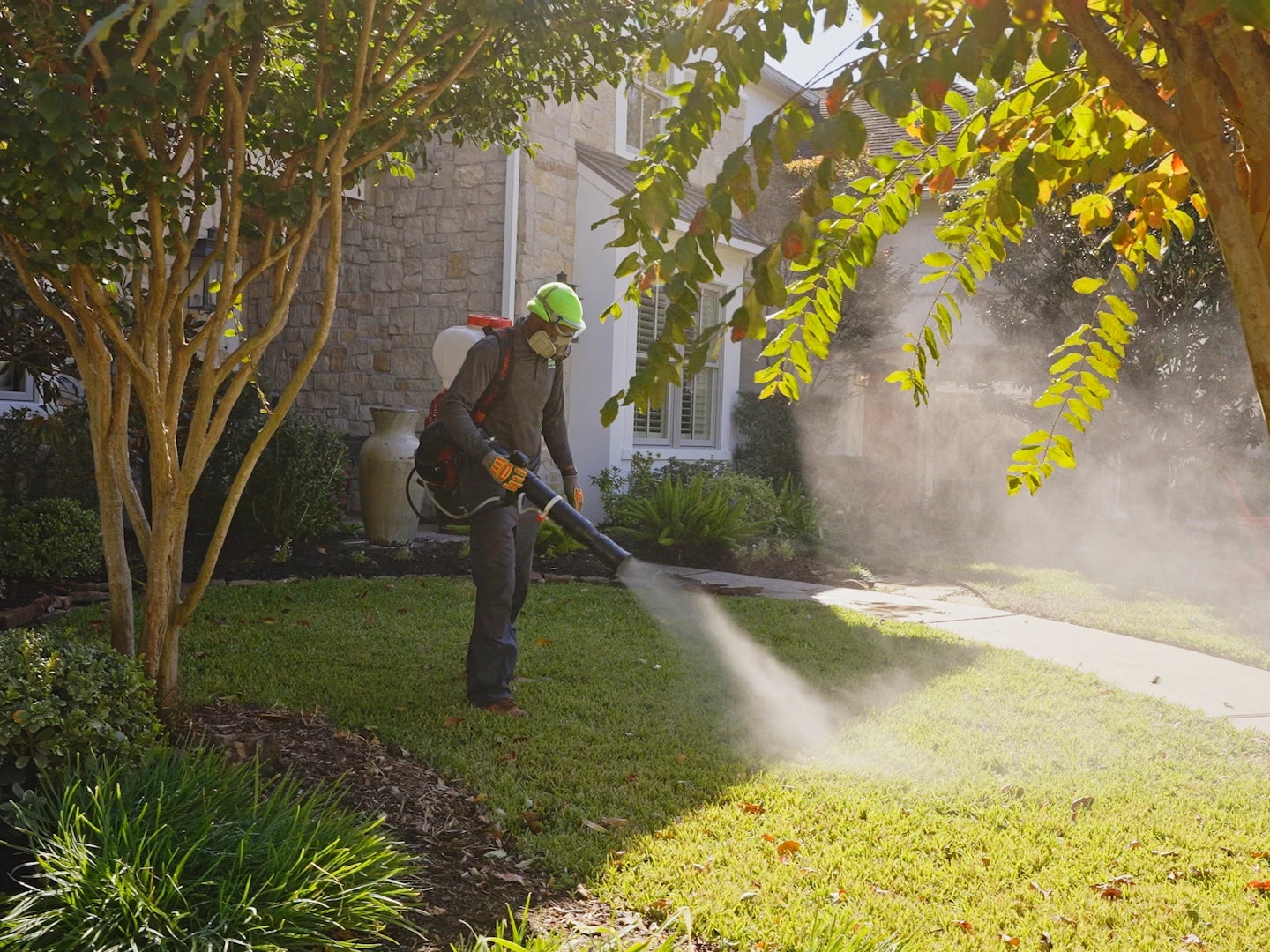 A technician applying a perimeter treatment along a home's front walkway