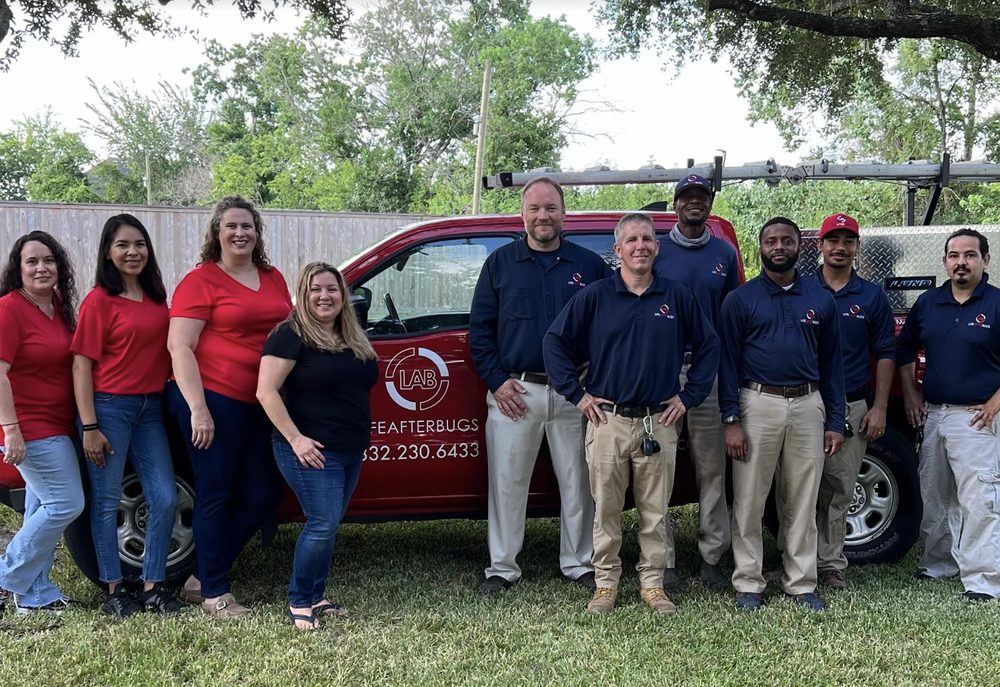 The full Life After Bugs team — office staff and technicians — standing together on a lawn in front of a red service truck